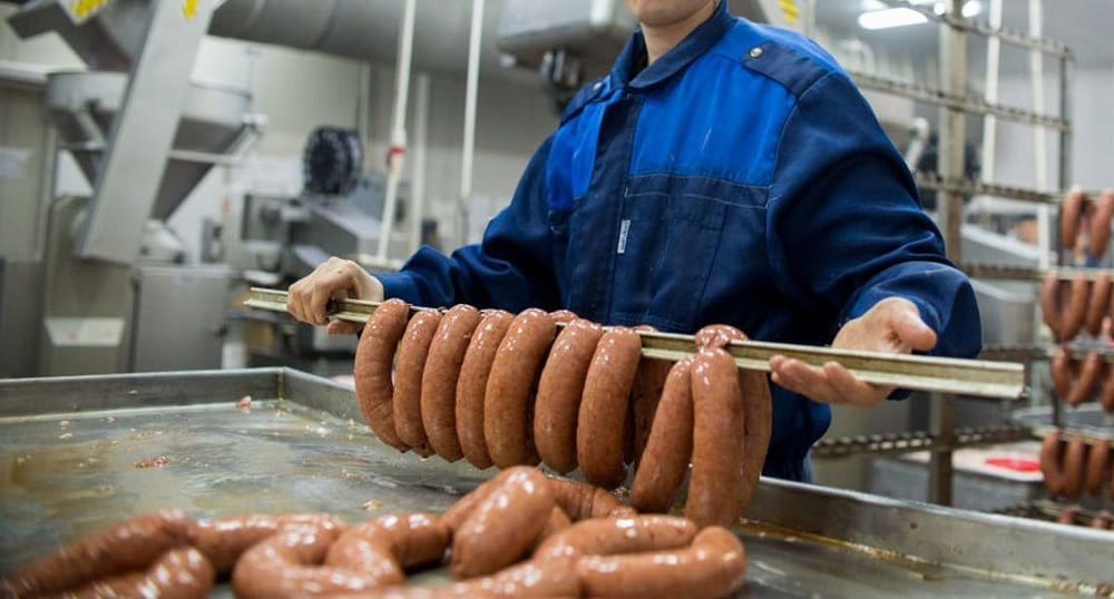 Подвешивание готовых сарделек на производстве Сардельки на заводе