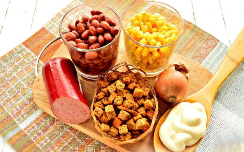 Копчёная колбаса, фасоль, кукуруза, сухарики, луковица и майонез для салата Состав салата с копчёной колбасой, фасолью и кукурузой