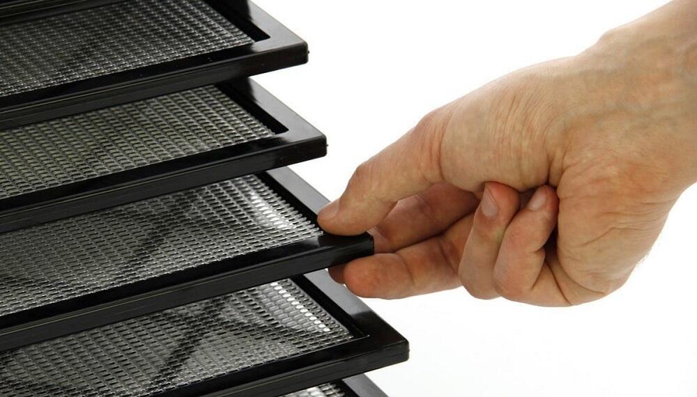 Дегидратор для сушки лаврового листа Человек вытаскивает решетки дегидратора