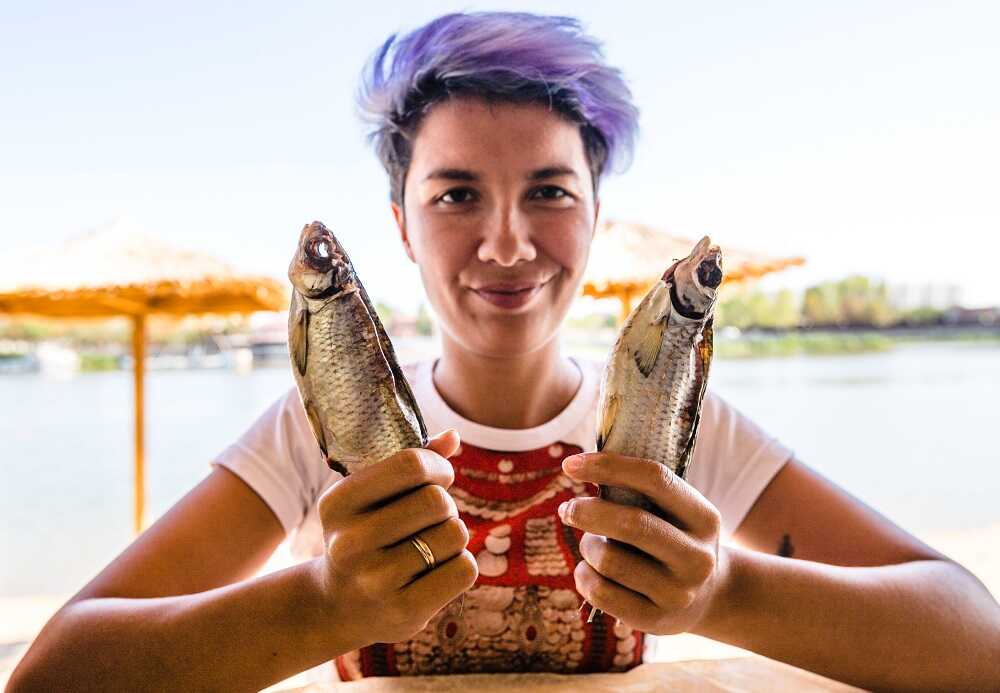 Вобла у молодой девушки Девушка держит в руках две воблы