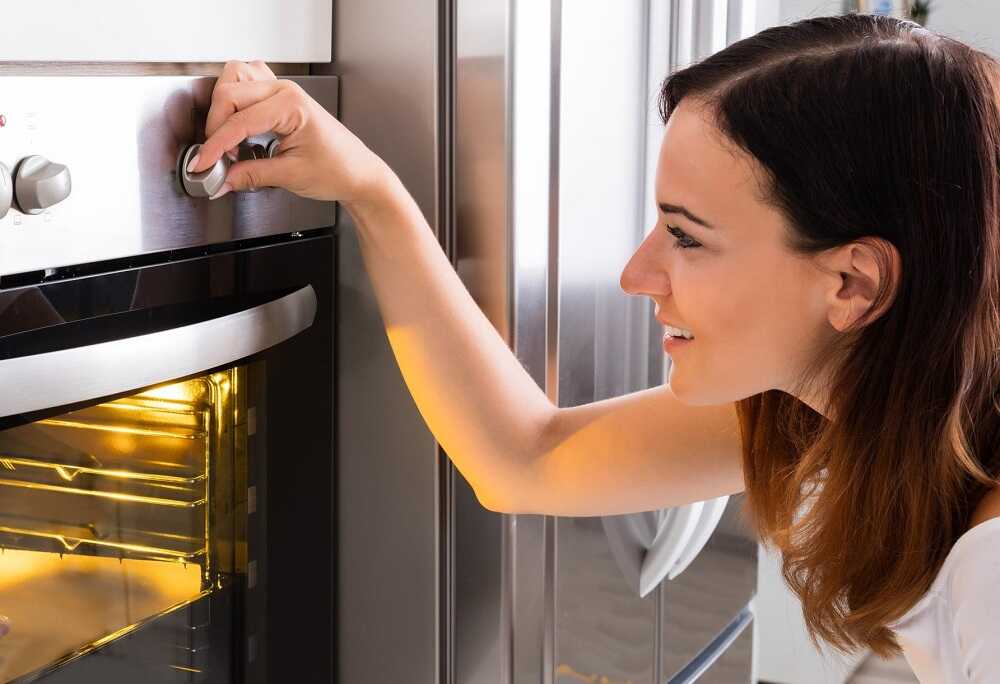 Приготовление сушеной дыни в духовке Девушка выставляет температуру духовки