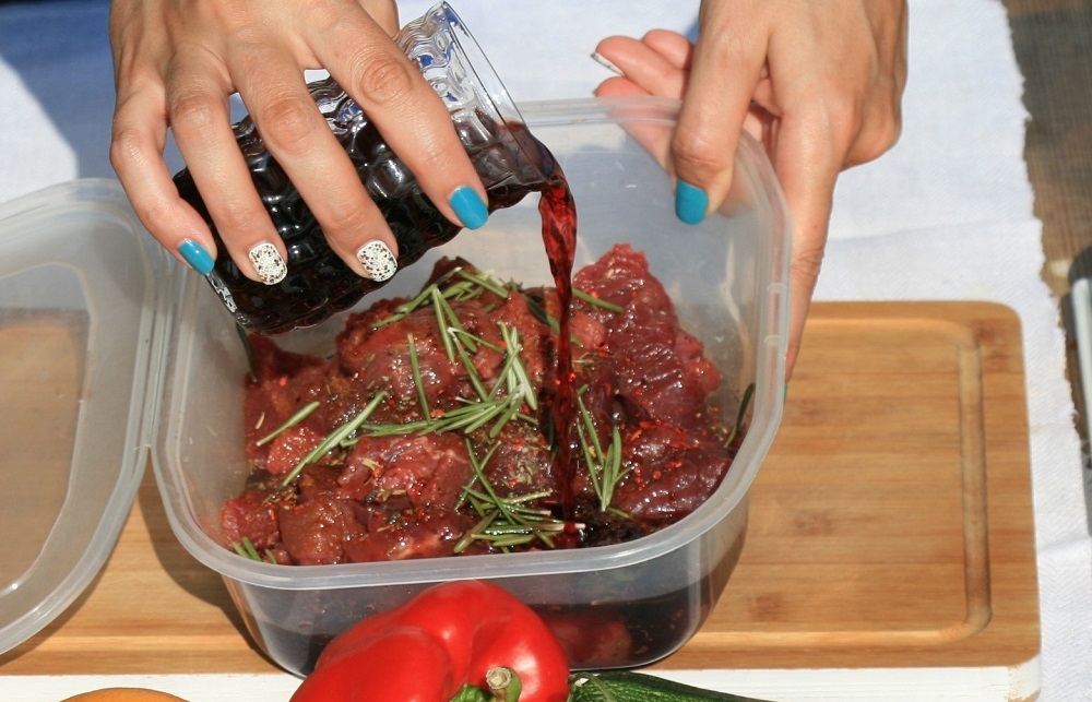 Маринад для мяса из уксуса, вина и специй Девушка заливает мясо маринадом