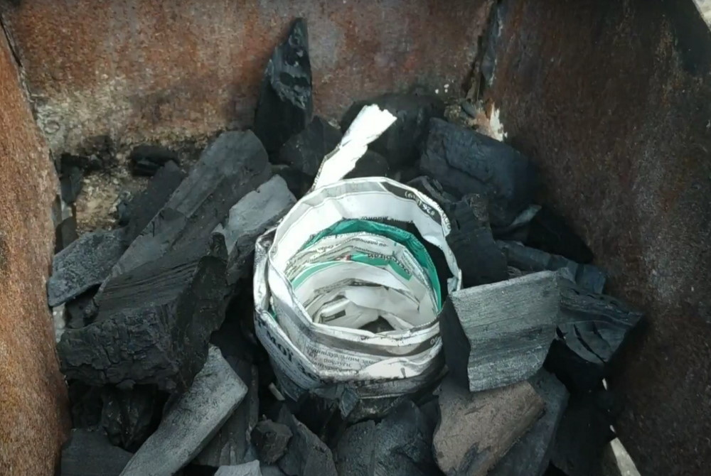 Газета сложенная по спирали для розжига углей Газета сложенная по спирали в углях