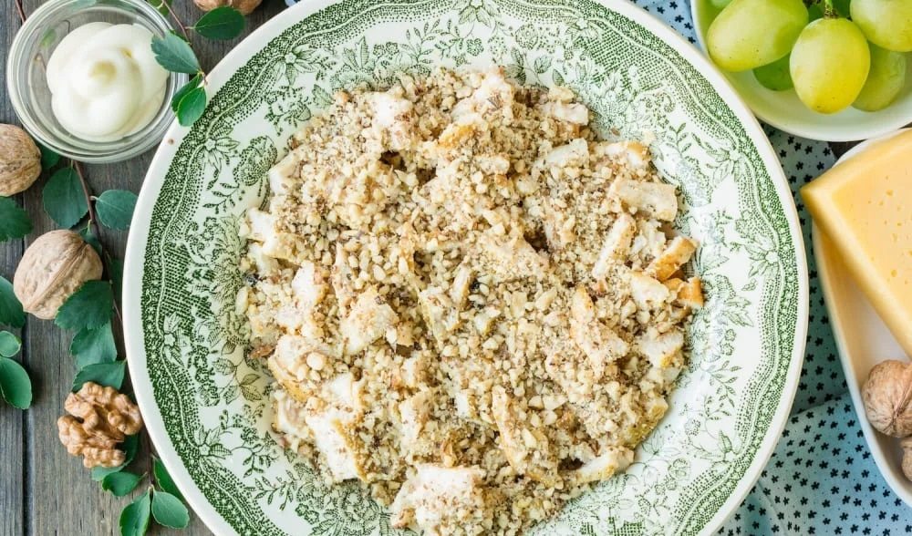 Куриный слой, посыпанный измельчёнными грецкими орехами Копчёная курица с грецкими орехами