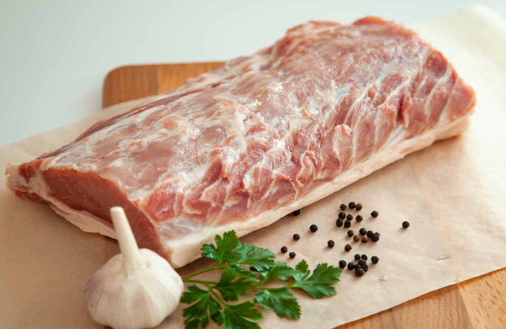 Свежий кусок свиного карбонада На листе пергамента свежий кусок свинины