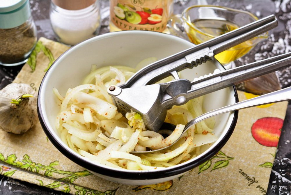 В миске нарезанный лук с чесноком В белой миске нарезанный лук с чесноком и пряностями