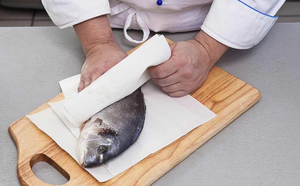 Обтирание рыбы салфетками Мужчина вытирает рыбу салфетками