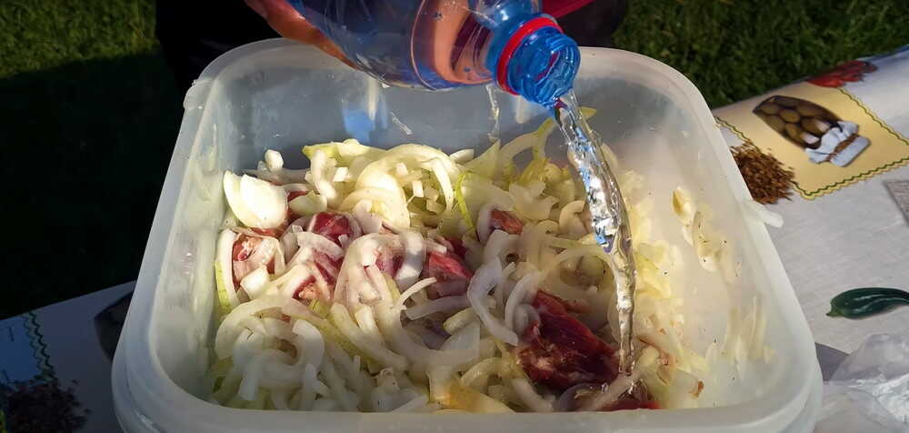 Мясо заливают минеральной водой В миске замаринованное мясо с луком поливают минеральной водой