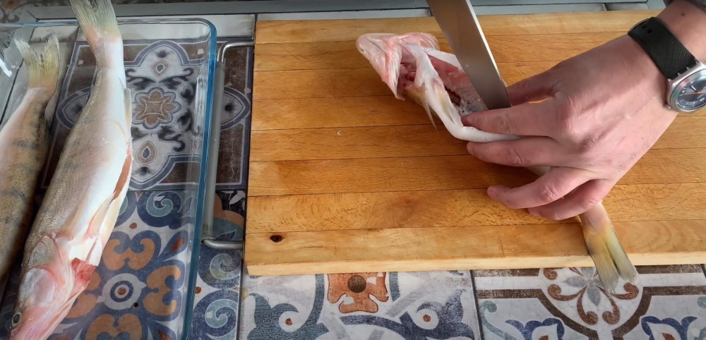 Процесс разделки тушки Повар вскрывает брюшко рыбе и извлекает все внутренности