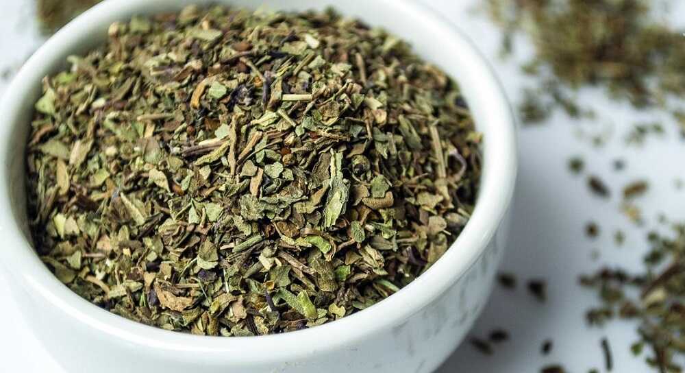 Мелкая смесь сушеного базилика Сушеный базилик в белой миске