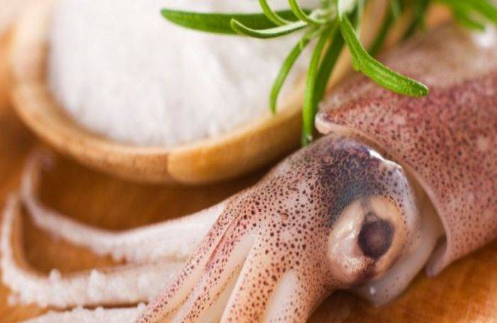 Свежий кальмар с солью На деревянном столе кальмар с солью