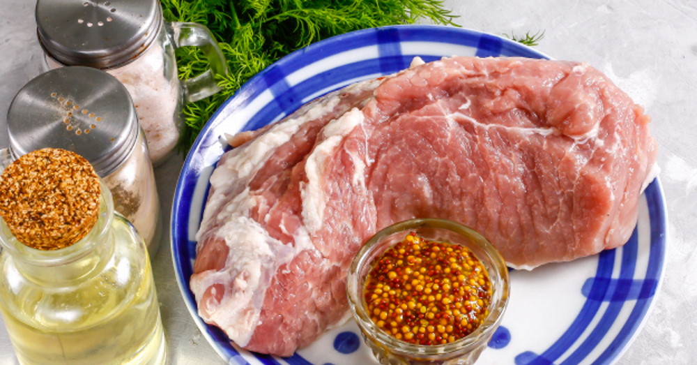 Свежий кусок свинины с горчицей На тарелке лежит свежий кусок свинины с зернистой горчицей