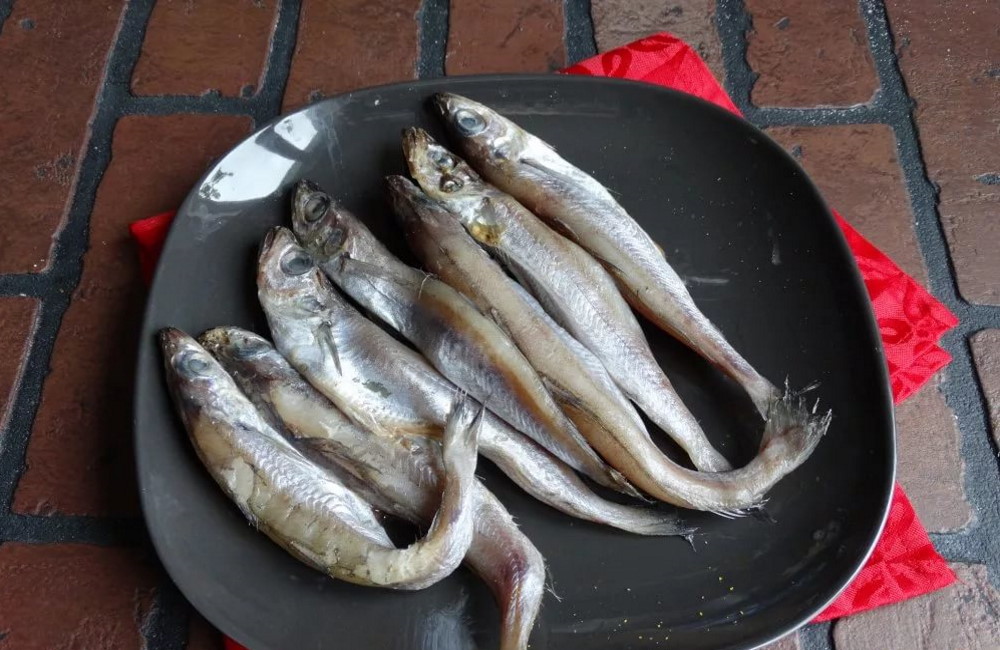 Размороженная рыба путассу На черной тарелки тушки путассу