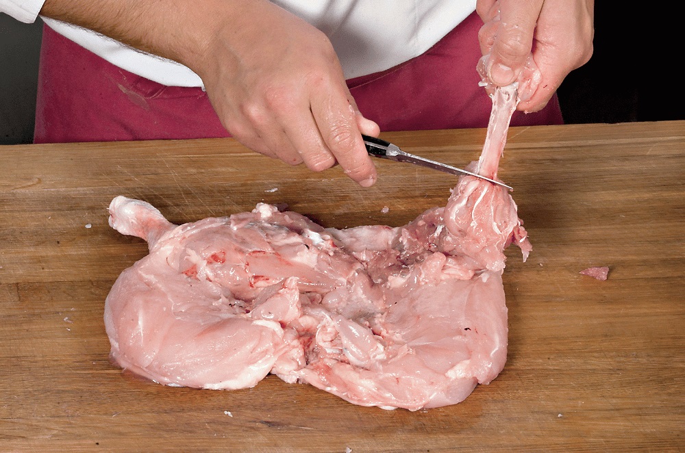 Подготовка мяса к приготовлению Женщина разделывает мясо кролика